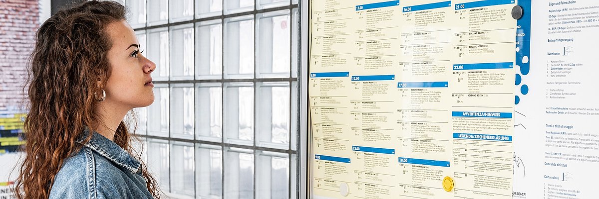 A girl is cheking the train timetable at the station