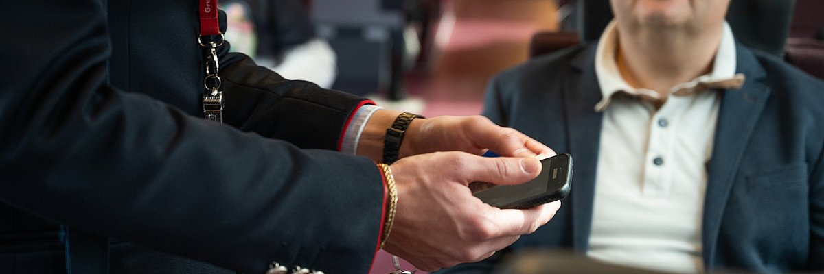 A ticket inspector checks a ticket using his smartphone.