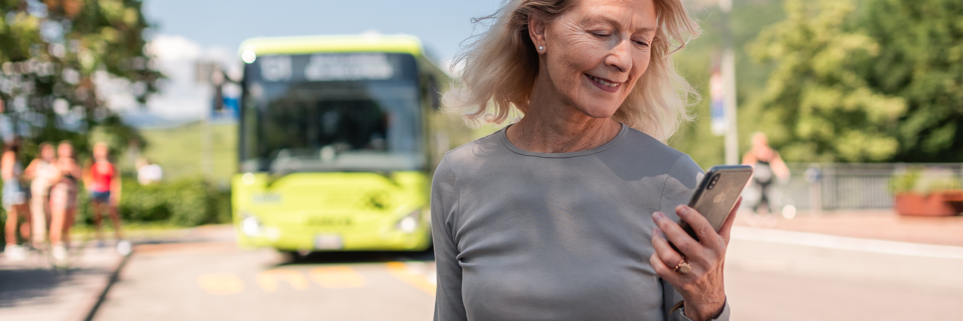 Woman with mobile next to a bus